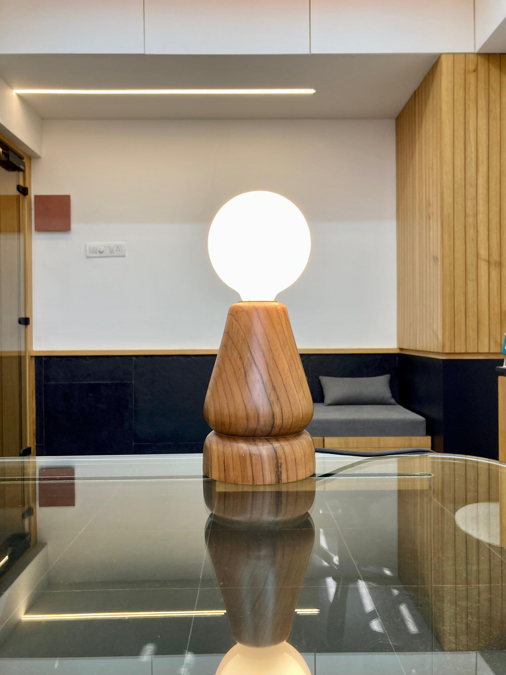 sangath - teak wood table lamp by advit design lab - placed on glass table