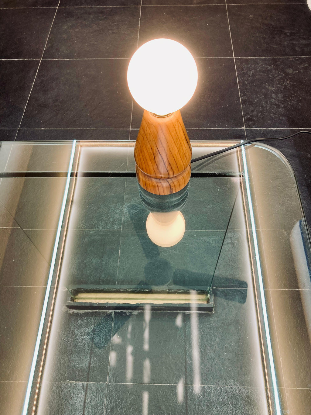 sangath - teak wood table lamp by advit design lab - placed on glass table